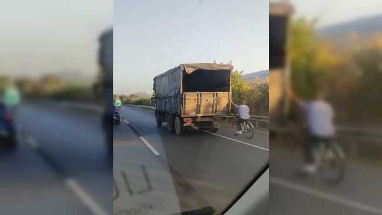 Hızla giden kamyonun arkasına tutunan bisikletli yürekleri ağza getirdi