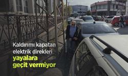 Kaldırımı kapatan elektrik direkleri yayalara geçit vermiyor